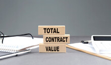 TOTAL CONTRACT VALUE Text On Wooden Block With Notebook,chart And Calculator, Grey Background