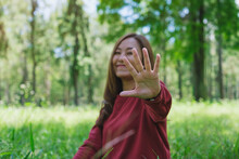 Portrait Image Of A Beautiful Young Asian Woman Do Outstretched Hand Or Making Stop Hand Sign While Playing With Camera In The Park