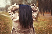 Portrait Of Brunette Hair Woman In Beige Coat Walking At The City Park .
