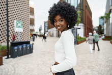 Portrait Of Young African Woman With Afro Hairstyle Smiling In Urban Background
