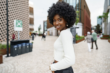 Portrait of young african woman with afro hairstyle smiling in urban background