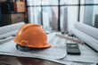 © Charnchai saeheng - Engineer safety helmet with drawings inspection on the office desk and Calculator, triangle ruler, safety glasses, compass on Blueprint. Engineer, Architect, Industry and factory concept.