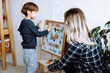 © Татьяна Волкова - Little boy and educator playing and studying numbers, letters and alphabet on magnetic board in playroom backview. Interesting lesson for kindergartners developing logic and intelligence