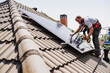 © Westend61 - Electricians installing solar panels on rooftop of house