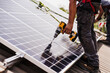 © Westend61 - Electrician using power tool for installing solar panel on rooftop