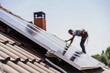 © Westend61 - Electrician installing solar panels on roof