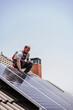 © Westend61 - Electrician installing solar panels on roof