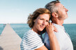 © Westend61 - Smiling mature woman standing with man at jetty on sunny day