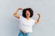 © Westend61 - Cheerful young woman flexing muscles in front of white wall