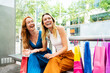 © Westend61 - Happy friends with shopping bags at bench outside mall