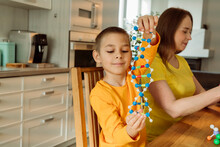 Boy Holding DNA Model By Mother At Home
