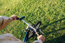 Hands of woman on handlebar riding bicycle in park