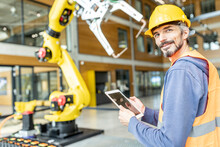 Confident Skilled Worker Controlling Robot Arm With Digital Tablet