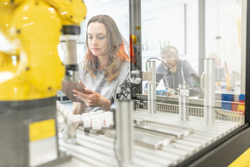 Woman working in robotic factory using digital tablet