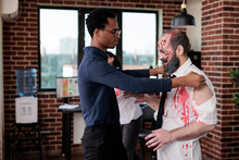 Creepy Eerie Zombie Talking To Man At Workplace, Macabre Cruel Monster Corpse In Business Office Acting Aggressive And Dangerous. Scary Undead Devil With Bloody Wounds In Company Space.