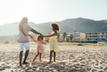 Father With Daughters Playing Ring Around Rosy At Beach