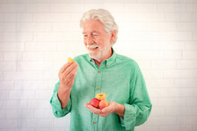 Handsome Elderly White-haired Man Holding Some Apricots In One Hand And Half Fruit In The Other Hand - Healthy Eating And Diet Concept