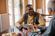 © Drazen - Black senior man talks to his friend during lunch at residential care home.