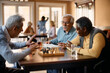 © Drazen - Senior man talks to his friends who are playing chess at nursing home.