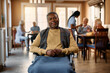 Smiling black senior in wheelchair at nursing home looking at camera.