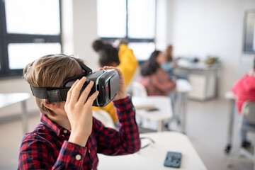 Wall Mural - curious student wearing virtual reality goggles at school in computer science class