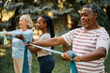 © Drazen - African American senior man using resistance band during exercise class in backyard of nursing home.