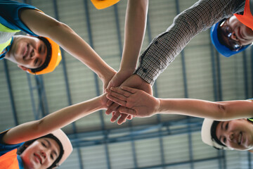 Group of industrial warehouse asian worker in safety suite hand stack celebrate successful or deal commitment. Logistics , supply chain and warehouse business.Teamwork unity under view concept.