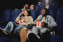 Young Gen Z Black Man And Caucasian Woman Wearing Casual Clothes Relaxing Watching Movie And Eating Popcorn At Cinema