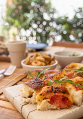 Tipical summer south Italian appetizer focaccia with cherry tomatoes and rucola served outdoor