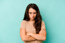 Young Caucasian Woman Isolated On Blue Background Frowning Face In Displeasure, Keeps Arms Folded.
