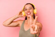 © Asier - Young caucasian woman listening to music isolated on pink background