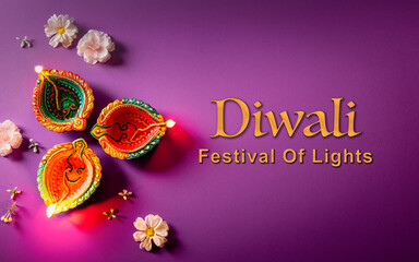 Happy Diwali - Clay Diya lamps lit during Dipavali, Hindu festival of lights celebration. Colorful traditional oil lamp diya on purple background