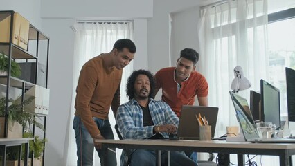 Wall Mural - medium slowmo of team of male indian programmers looking at laptop screen while discussing software 