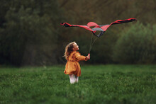Having Fun. Little Girl Is Running With Red Colored Kite Outdoors. Playful Mood