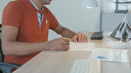 Wall Mural - cropped slowmo of unrecognizable man signing business documents while sitting by computer at office 
