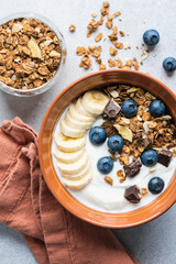 Wall Mural - Yogurt granola bowl with blueberries, banana and chocolate. Top view