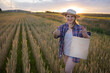 © olga_sova - A beautiful middle-aged farmer woman in a straw hat and a plaid shirt stands in a field of golden ripening wheat during the daytime in the sunlight
