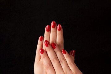 Wall Mural - Female hands with beautiful manicure - red nails on dark black background. Nail care concept