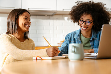 African american woman and daughter doing homework together at home