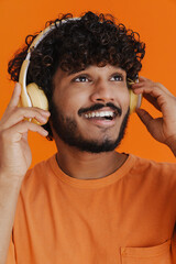 Wall Mural - Young handsome indian smiling man in headphones enjoying music