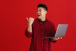 © Drobot Dean - Asian excited man using laptop and pointing finger aside