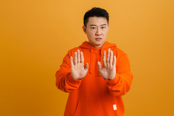 Wall Mural - Asian young man wearing hoodie showing stop gesture