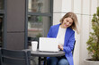 ©  QuantumMuse - Happy woman watching online media content on laptop sitting in a park