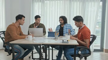Wall Mural - medium slowmo of four male indian colleagues having brainstorm while sitting around office desk toge