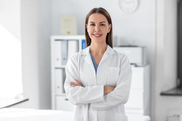 medicine, healthcare and profession concept - smiling female doctor with crossed arms at hospital