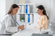© Syda Productions - medicine, healthcare and people concept - smiling female doctor or cardiologist with clipboard showing cardiogram to woman patient at hospital