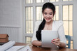 © skarie - Beautiful young Asian working with tablet computer at office desk or co working space. Business successful concept. Asian businesswoman holding tablet and she smiled in a good mood.