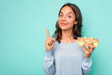 Young Hispanic Woman Holding Eggs Isolated On Blue Background Showing Number One With Finger.