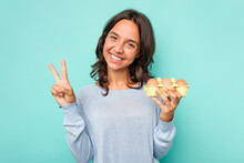Young Hispanic Woman Holding Eggs Isolated On Blue Background Showing Number Two With Fingers.