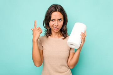 Wall Mural - Young hispanic woman holding kitchen roll isolated on blue background showing a disappointment gesture with forefinger.